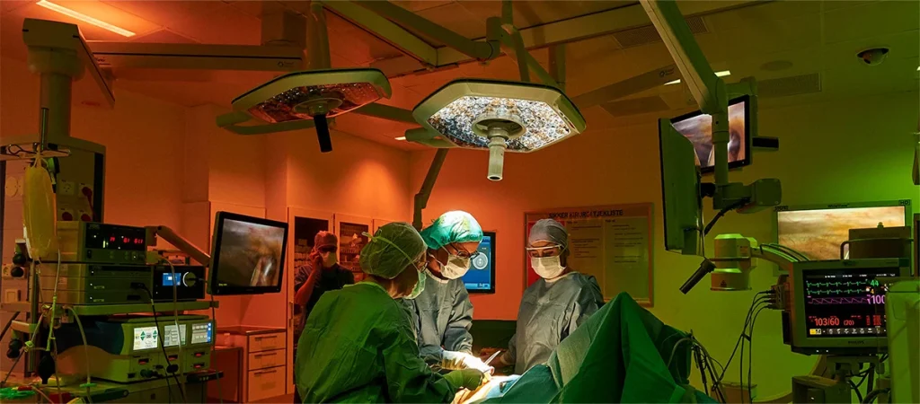 Ameliyathanede kırmızı ve yeşil zonlu aydınlatma altında operasyon gerçekleştiren cerrahi ekip